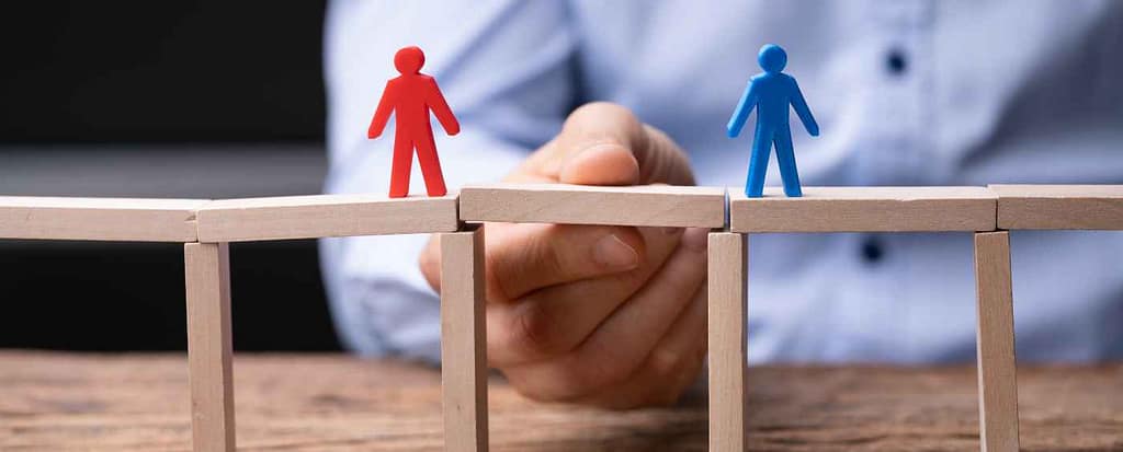 Su di un ponte di legno fatto con le costruzioni, ci sono due omini. Una persona unisce una distanza con un pezzo. Questo è ciò che simbolicamente fa la negoziazione. Unisce. La ragione è dei fessi, trovare un incontro è la chiave.