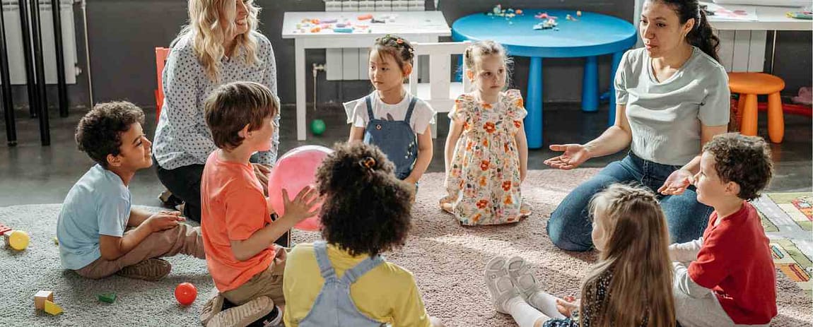 Due maestre, circondate da bambini stanno facendo lezione