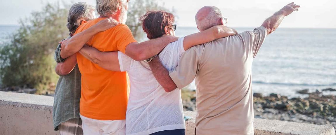 Longevità, patologie e dolore cronico Persone mature e anziane si abbracciano guardando l'orizzonte davanti a loro.