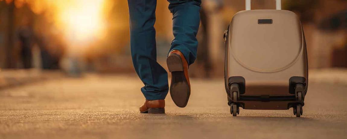 business travel: si vede un uomo che cammina con a fianco il suo trolley.