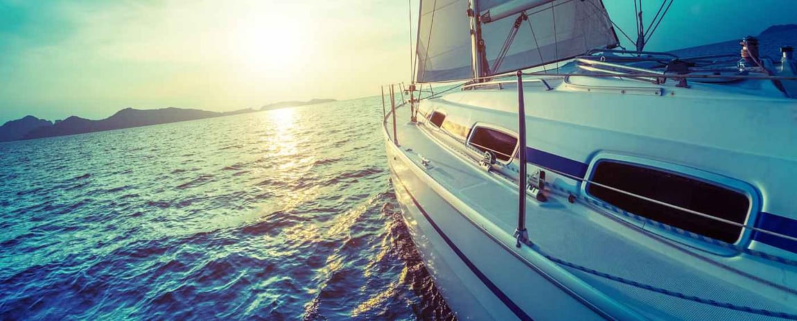 Una barca a vela che salpa a vele spiegate verso il sole.