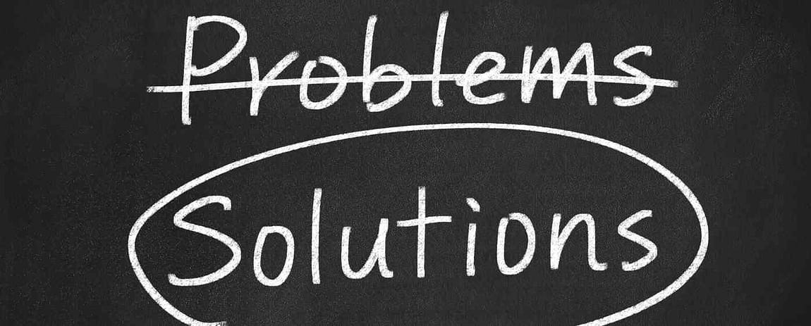 Come se fossero state scritte con un gesso bianco su di una lavagna, si leggono le parole "problems" barrata e "solutions" cerchiata