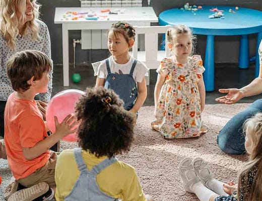 Due maestre, circondate da bambini stanno facendo lezione