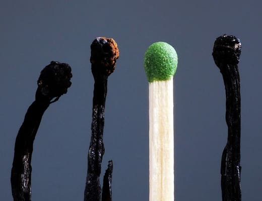 Burnout: come riconoscerlo e affrontarlo in modo strategico: una serie di fiammiferi bruciati con uno solo al centro integro rappresentano il concetto.