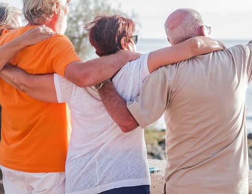 Longevità, patologie e dolore cronico Persone mature e anziane si abbracciano guardando l'orizzonte davanti a loro.