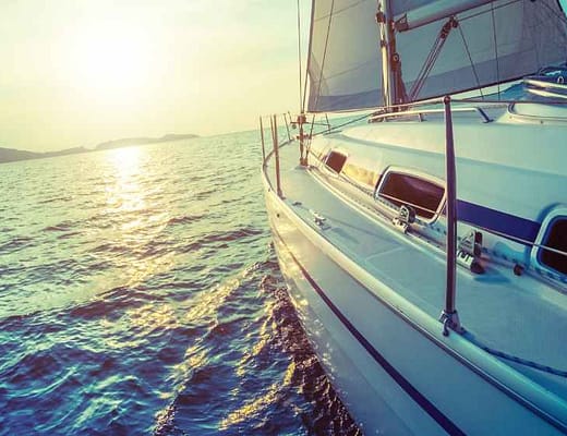 Una barca a vela che salpa a vele spiegate verso il sole.